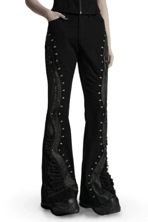 Black gothic flared pants with spike studs and mesh panels front three-quarter view on model