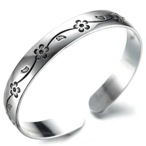 Silver plated open cuff bangle bracelet with gothic engraved floral vine pattern, 3/4 oblique view showing intricate flower details