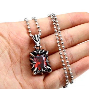 Close-up of gothic stainless steel gem pendant held in palm showing detail and faceted red stone