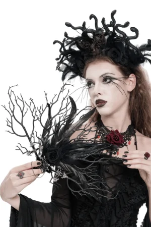 Black feather gothic hand fan with cross charms, three-quarter view worn by gothic model with dark makeup
