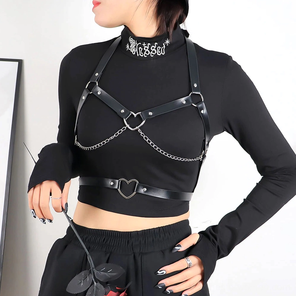 Woman posing with artificial rose holding gothic chest harness, side profile showing heart-shaped metal details