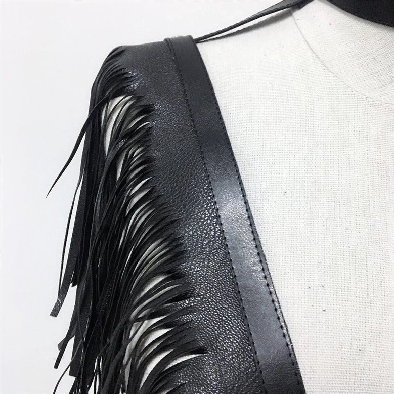 Side close-up detail of black leather harness shoulder showing fringe tassels, smooth leather texture, and metal hardware