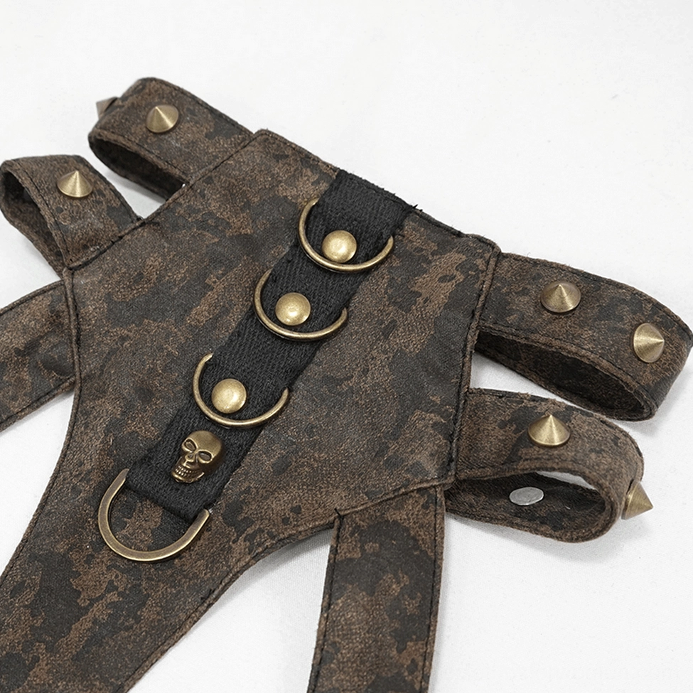 Detailed flat lay showing gothic harness strap with spike stud decorations, D-ring metal hardware, and distressed brown leather