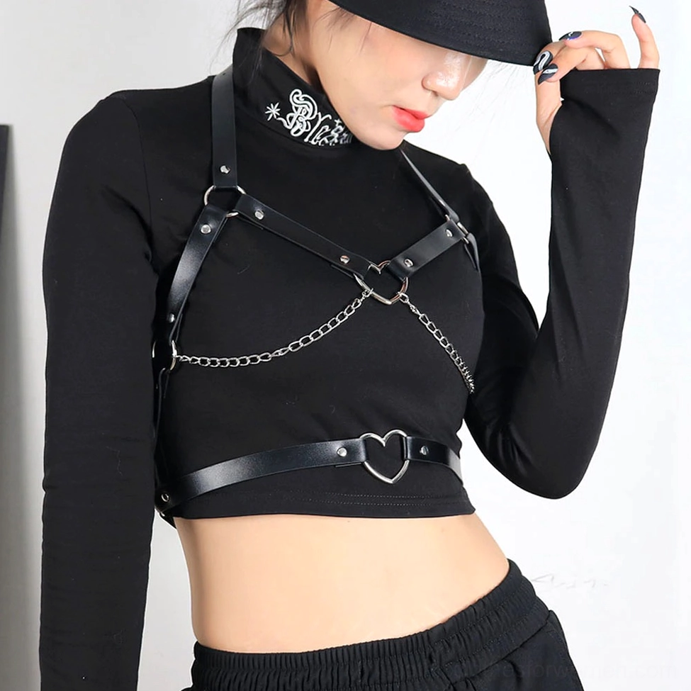 Woman wearing black gothic harness with crop top and street style outfit, side view with heart metal details