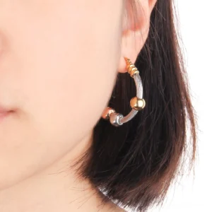 Woman wearing twisted gothic hoop earrings in profile, close-up showing dual-tone metal accents and daily wear styling