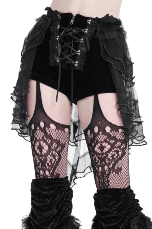 Black gothic lace-up ruffled shorts with tulle overlay and tie detail, front view with fishnet stockings on white background