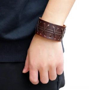 Brown genuine leather gothic cuff bracelet worn on wrist, showcasing cross-stitch detailing and adjustable snap closure from side view