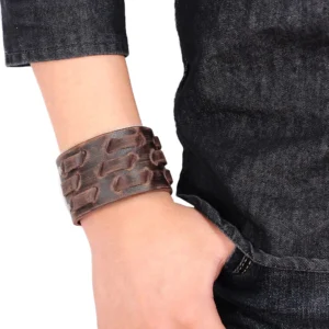 Brown gothic leather cuff bracelet worn on male wrist with dark denim, showcasing authentic distressed finish and vintage punk aesthetic