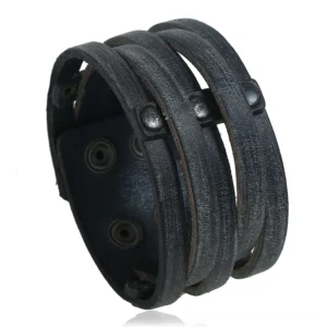 Wide black leather gothic cuff bracelet with metal rivets, triple-strap design, overhead view on white background