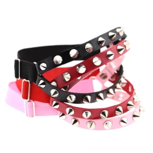 Multi-color spiked leg garters display featuring black, red, pink, and blue leather options with silver cone and round rivets in overhead flat lay