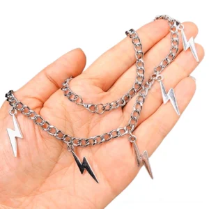Close-up detail of silver and gunmetal lightning charm pendants held in palm, showing intricate geometric design and craftsmanship
