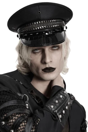 Black studded gothic military cap with glossy patent visor, front close-up view worn by androgynous goth model