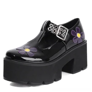 Front three-quarter view of black patent leather gothic platform pumps with purple flower appliqués and silver metal buckle T-strap detail