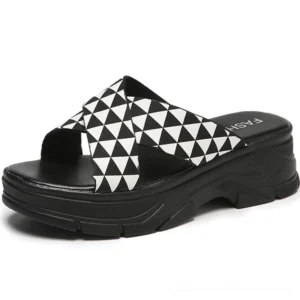 Black and white geometric crisscross platform slides with bold triangle print straps and thick rubber outsole, front angle view