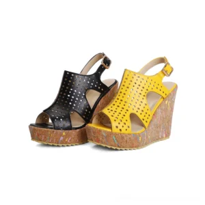 Black and yellow gothic platform wedge sandals with perforated cutout design displayed on white background, front view showing ankle buckle strap and cork sole