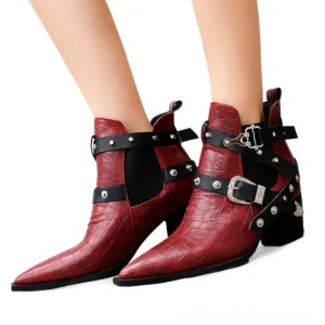 Women's gothic pointed toe chunky heel ankle boots with metal buckles and rivets, shown on model legs from low angle view