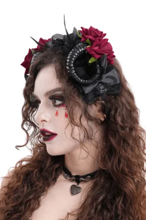 Three-quarter side view of gothic horned floral headpiece with spiral black ram horns and black satin bow accent on model with curly brown hair