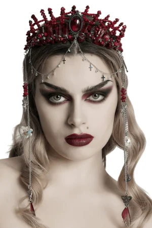 Gothic red crystal crown with silver cross face chains worn by model with dramatic dark makeup, front half-body studio portrait