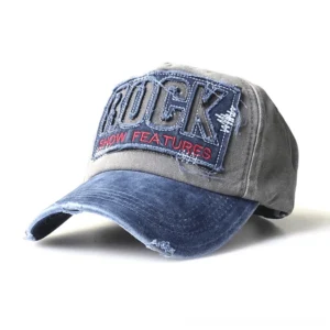 Alternative rock baseball cap in navy blue and gray denim, worn distressed style with frayed edges and bold embroidered patch, front angle perspective