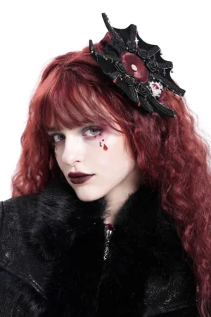 Gothic rose cross hair clip with burgundy details worn by model with curly red hair, left side portrait view showcasing spiderweb lace design