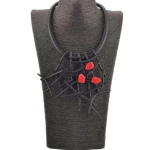 Statement gothic choker featuring black elasticity rope chain with red wooden beads and branch design worn on dark fabric backdrop
