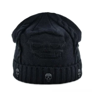 Black gothic skull knit beanie with embossed skull pattern and metal badge, front flat lay view