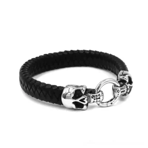 Black gothic double skull bracelet side view, asymmetric dual skull clasp design on braided leather band with stainless steel hardware