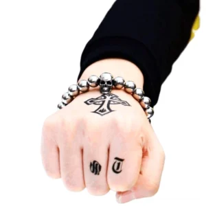 Gothic skull bead bracelet on tattooed male wrist - dark aesthetic jewelry styling on inked hand