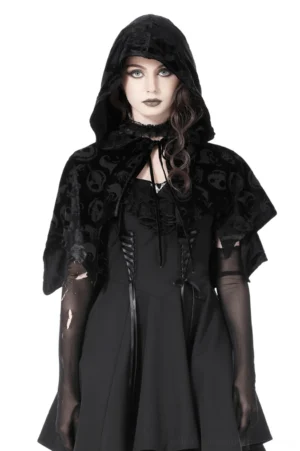 Black velvet gothic hooded cape with embossed skull print, front view on model showcasing draped silhouette and bat-wing hem design