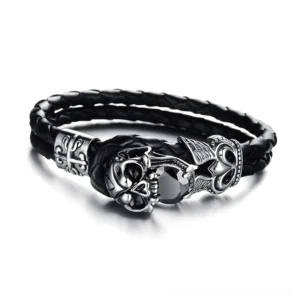 Skull charm genuine leather gothic bracelet with winged stainless steel design, three-quarter side view showing braided black leather and silver metal accents
