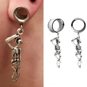 Skull ear tunnel worn on human ear – bright polished silver skeleton earring hanging from piercing, close-up detail shot