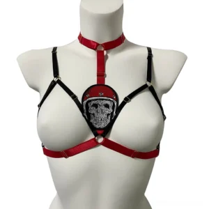 Black and red skull bondage body harness front view on mannequin, featuring embroidered skull detail with metal ring fasteners and adjustable elastic straps