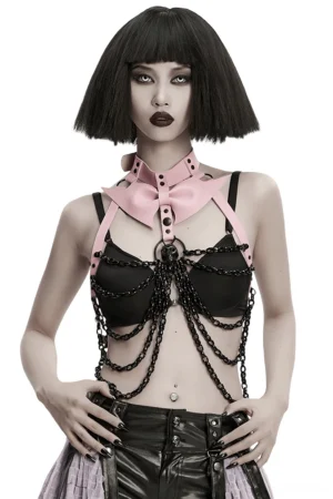 Front view of black and pink gothic skull chest harness with detachable bat bow and draped chain details on female model