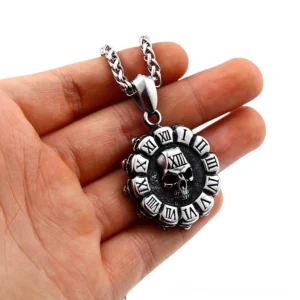 Gothic skull pendant with Roman numeral frame in polished stainless steel, shown held in hand against white background, displaying intricate embossed skull carving and spiked circular border
