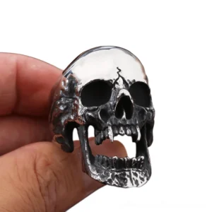 Biker skull ring on human finger, aged silver with black darkened cracked details, close-up front view