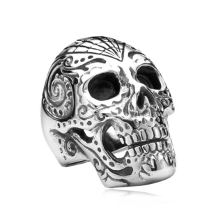 Memento mori carved sugar skull ring in silver stainless steel with intricate swirling engraved details and floral patterns, front overhead flat view