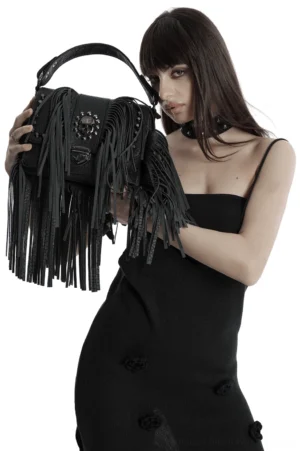 Black gothic skull tassel crossbody bag worn by woman in black slip dress - left three-quarter view