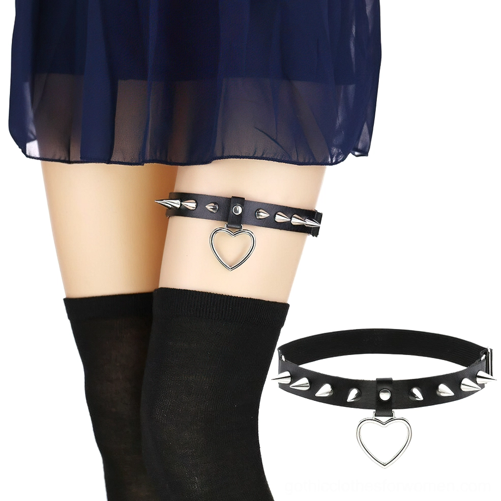 Black spiked heart leg garter belt worn on model's thigh with silver metallic studs and hollow heart pendant, styled with gothic fashion