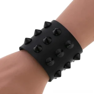 Black gothic spike studded leather wrap bracelet worn on mannequin wrist showing conical studs and snap button closure side view
