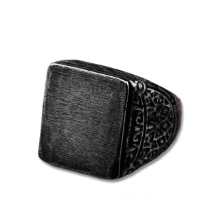 Dark gothic square stainless steel ring with brushed flat top and carved ornamental details, front side view against white background