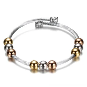 Two-tone gothic stainless steel cuff bracelet with twisted cable band and round metal beads in gold and silver finish, flat lay top view