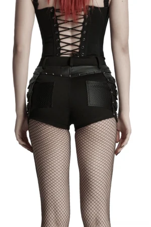Back view of gothic black studded high-waist shorts with mesh pockets and rivet trims, worn with lace-up corset by red-haired model - full body shot
