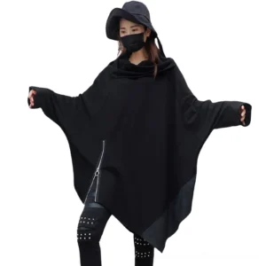 Female model wearing black asymmetrical gothic sweatshirt with batwing sleeves, studded pants and bucket hat, full-body front view