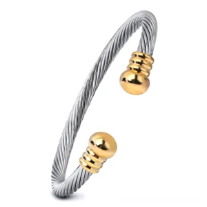 Two-tone twisted cuff bracelet with gold and silver finish, ribbed spherical end caps on white background