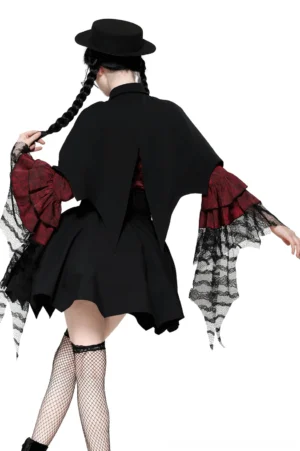 Back view of black gothic vampire cape on model with twin braids, displaying split back design, pointed bat-wing hem, and fishnet stockings