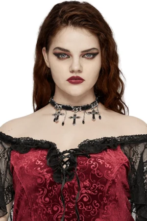 Gothic black velvet choker with ornate silver cross pendant and chain tassels worn by model with dark red curly hair