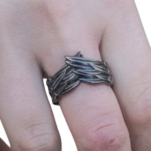 Dark gray gothic wing ring worn on male finger, side close-up view showcasing intricate carved feather details and oxidized metal finish