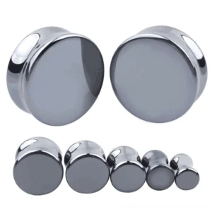Dark gray hematite stone ear gauges and flesh tunnel plugs in various sizes, polished gothic body jewelry displayed on white studio background