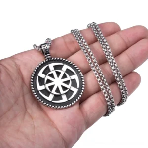 Kolovrat pendant held in hand showing scale and size - silver stainless steel with matching chain