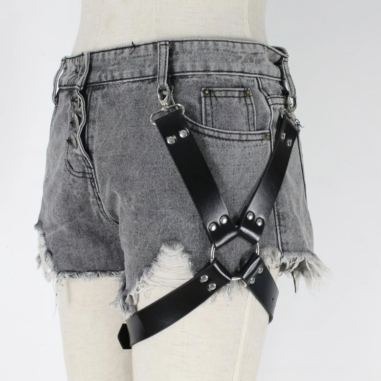Close-up detail of crossed black PU leather straps with metal studs on gothic leg harness, side profile